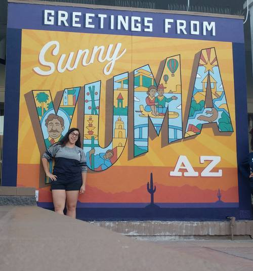 Courtney Daman 2015 graduate with minor in Spanish in front of Yuma, AZ sign